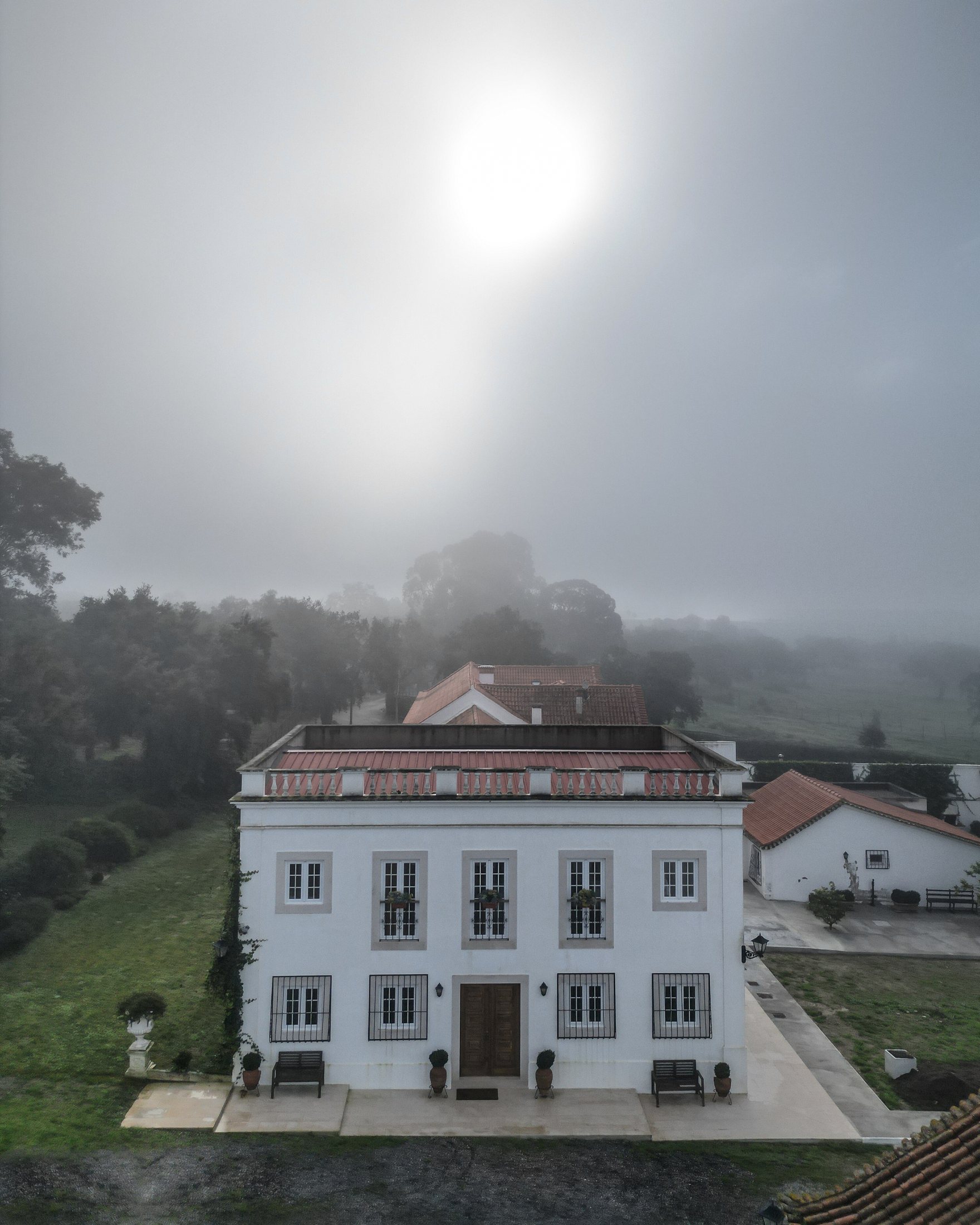The manor house in morning fog, seen from above.