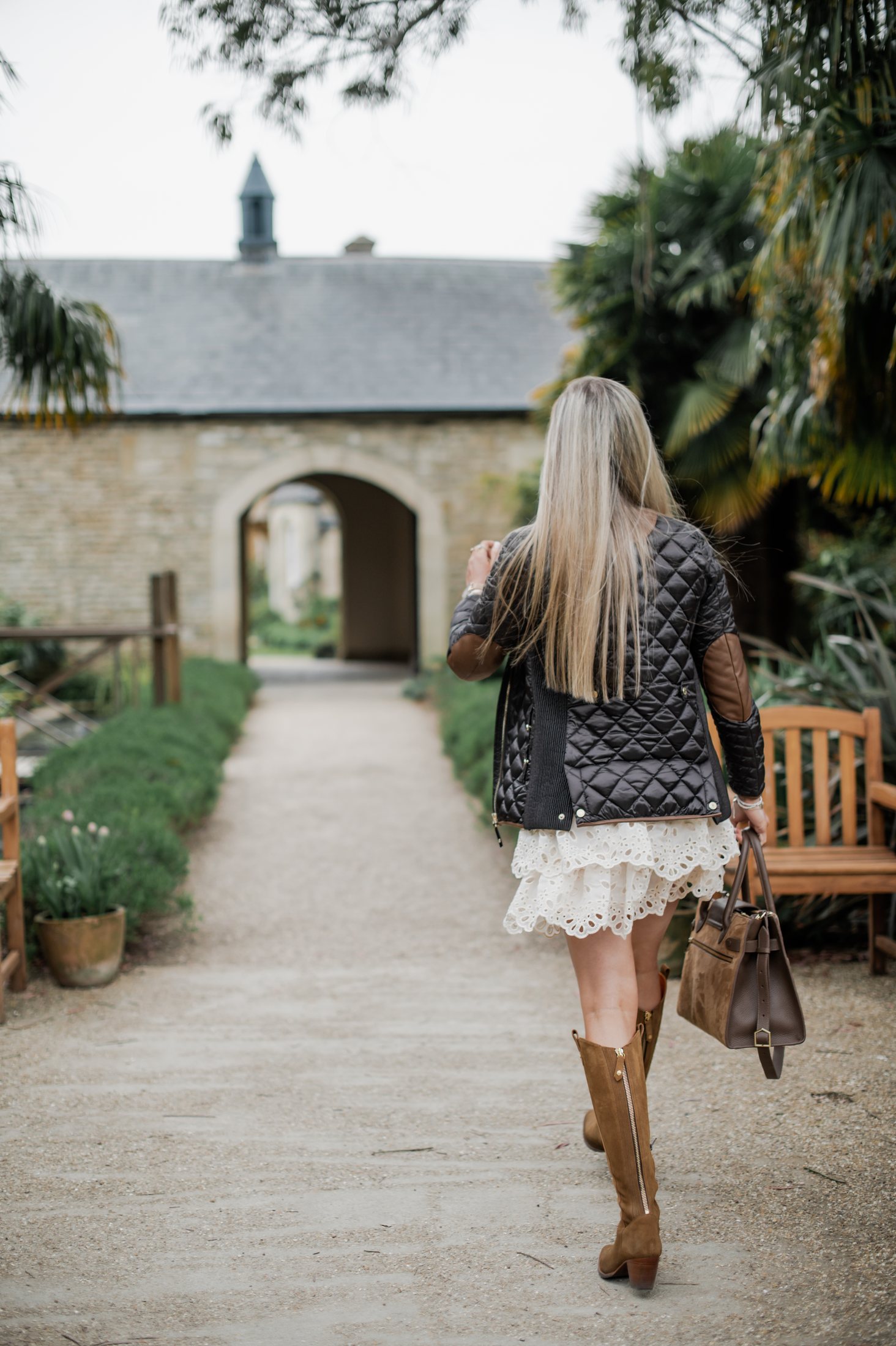 The guest walking away up the gravel path towards a stone archway.