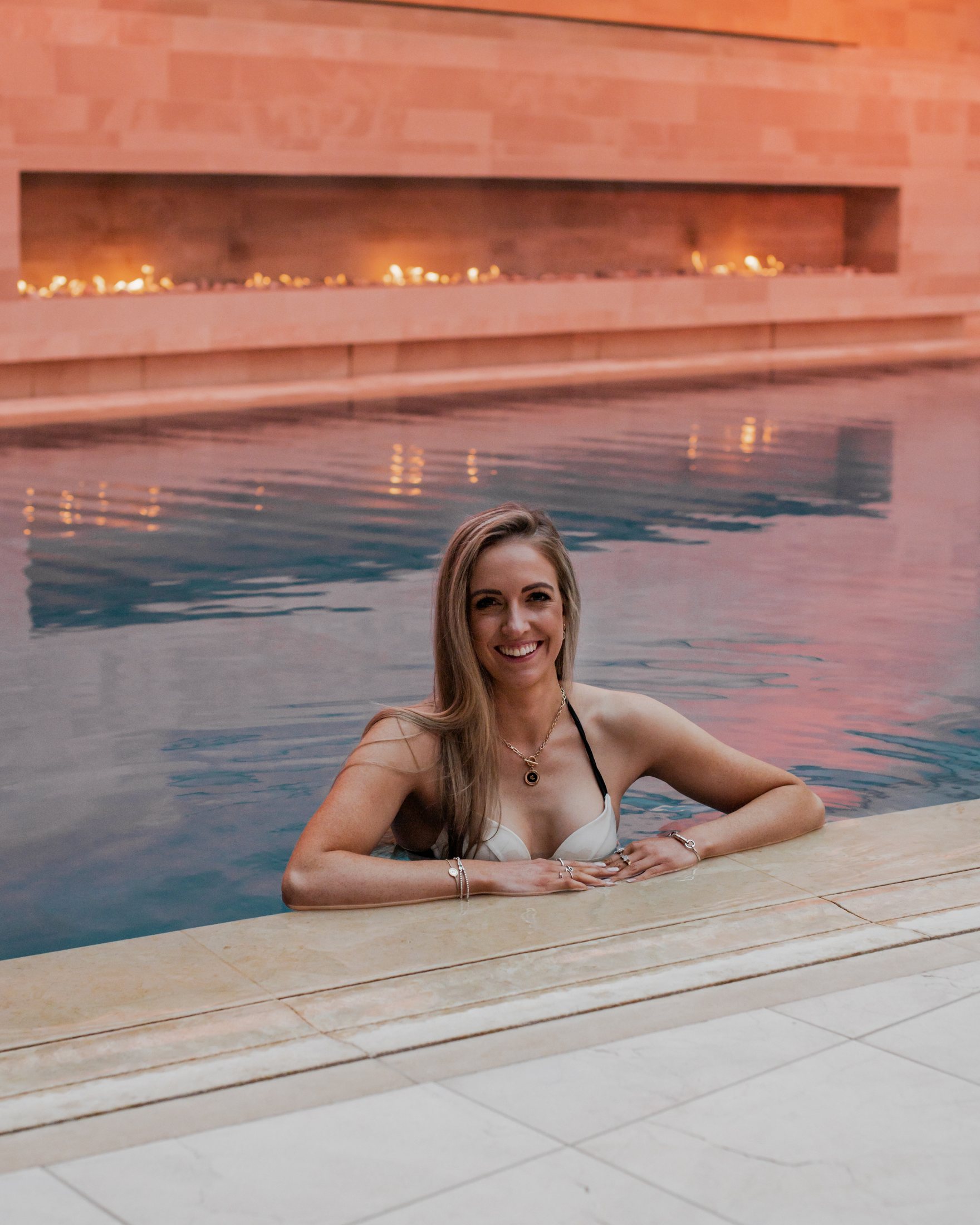 The spa pool at dusk, firelight on stone.